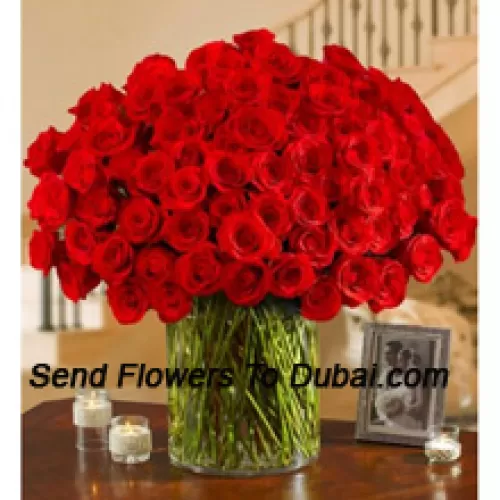 100 красных роз с папоротниками в большой стеклянной вазе